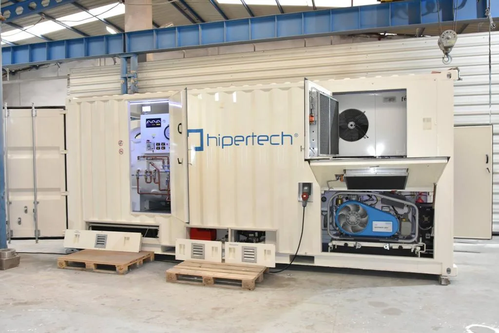 A Hipertech containerized system with its side doors and service hatches open, showing the chamber and console through one door and a compressor and air-handling unit in the bay at the far end