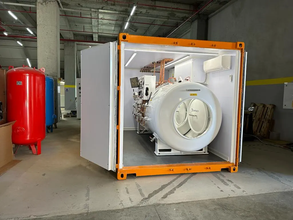 An orange-framed container with its doors swung open on the white chamber fitted inside it, in a workshop