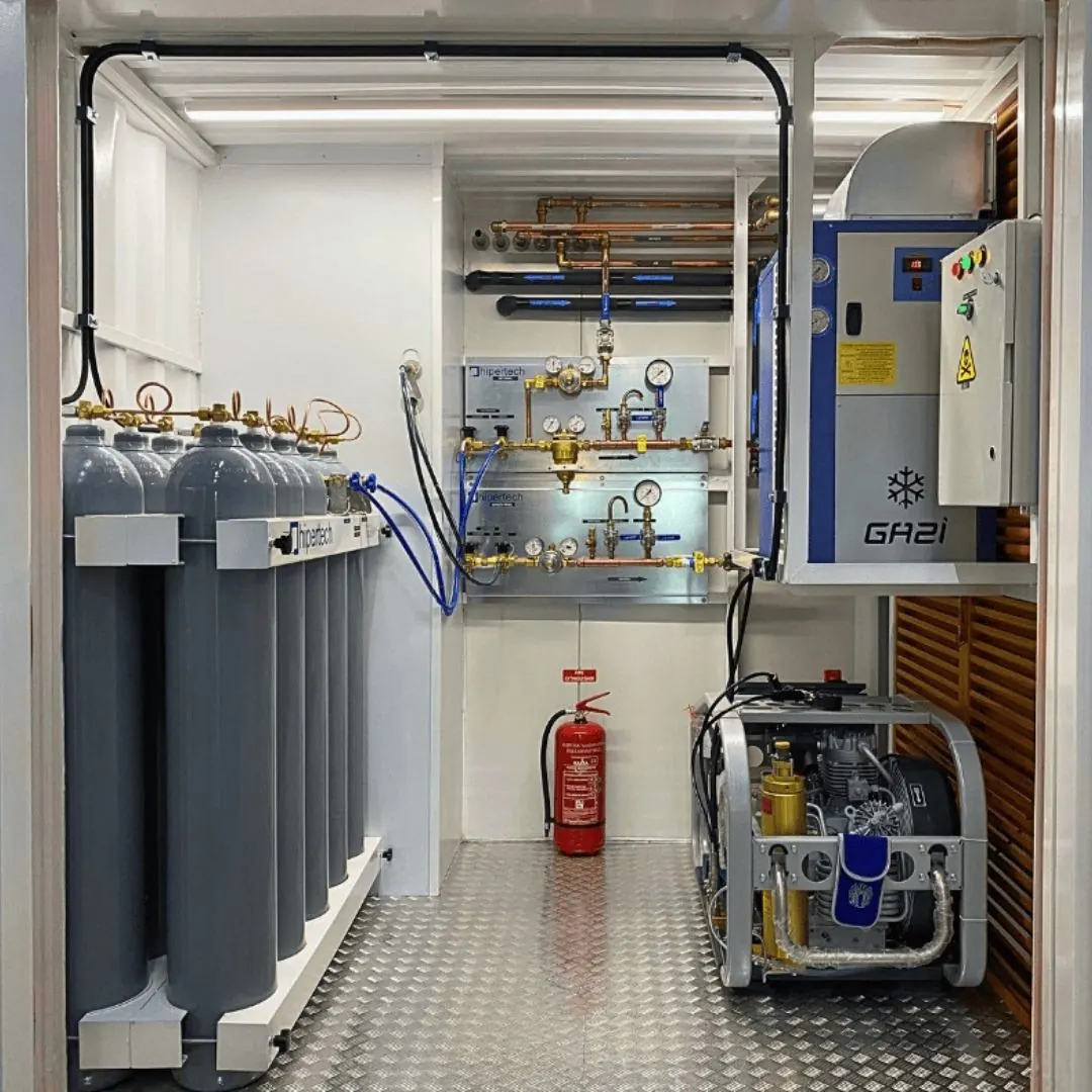 The technical bay of a containerized system: a rack of composite gas cylinders, a gas manifold, an air dryer cabinet and a compressor