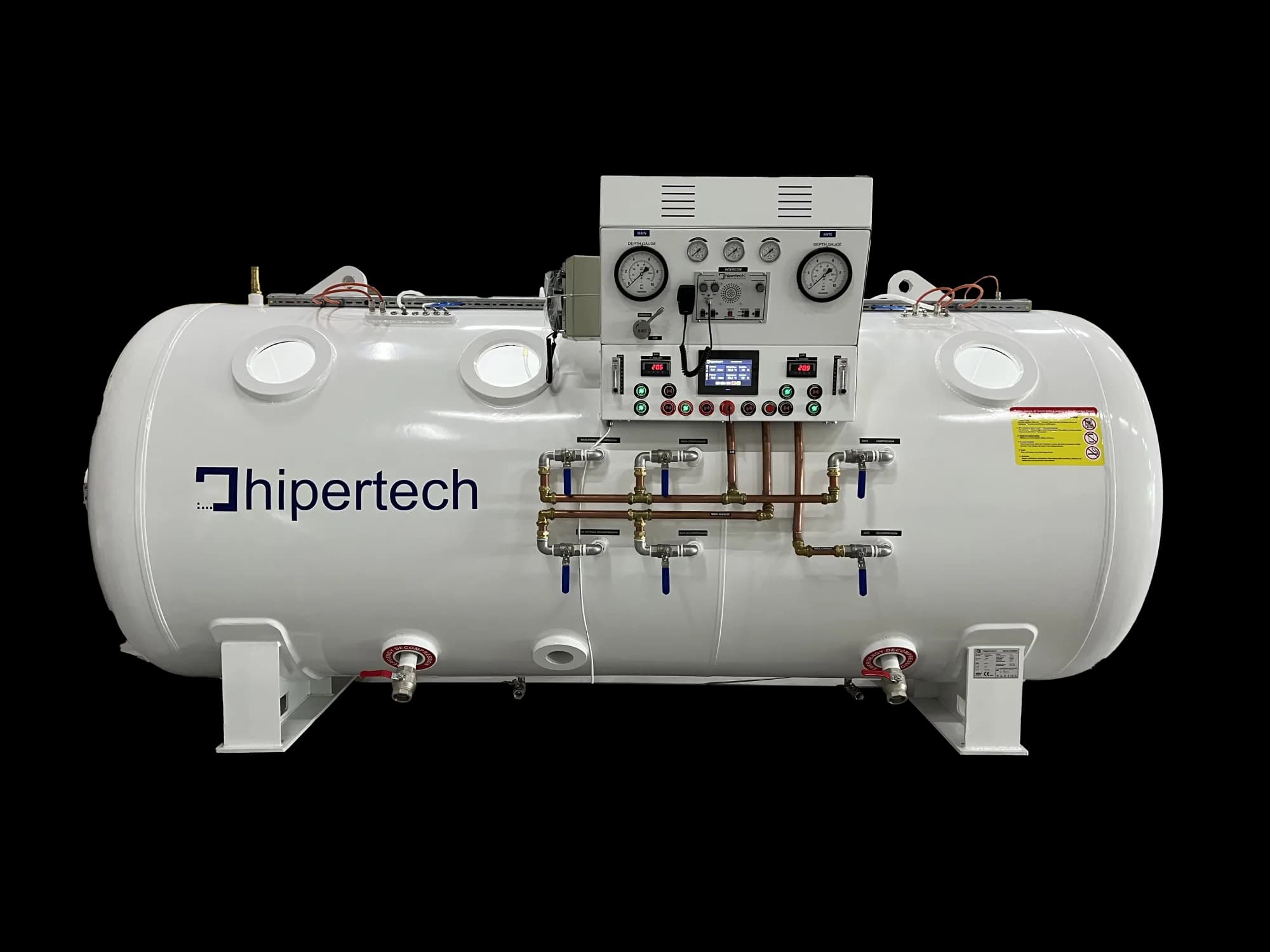 Side elevation of a Hipertech twin-lock decompression chamber: two viewports on the main lock, one on the ante-lock, and a console carrying a depth gauge for each lock above a run of labelled compression and decompression valves