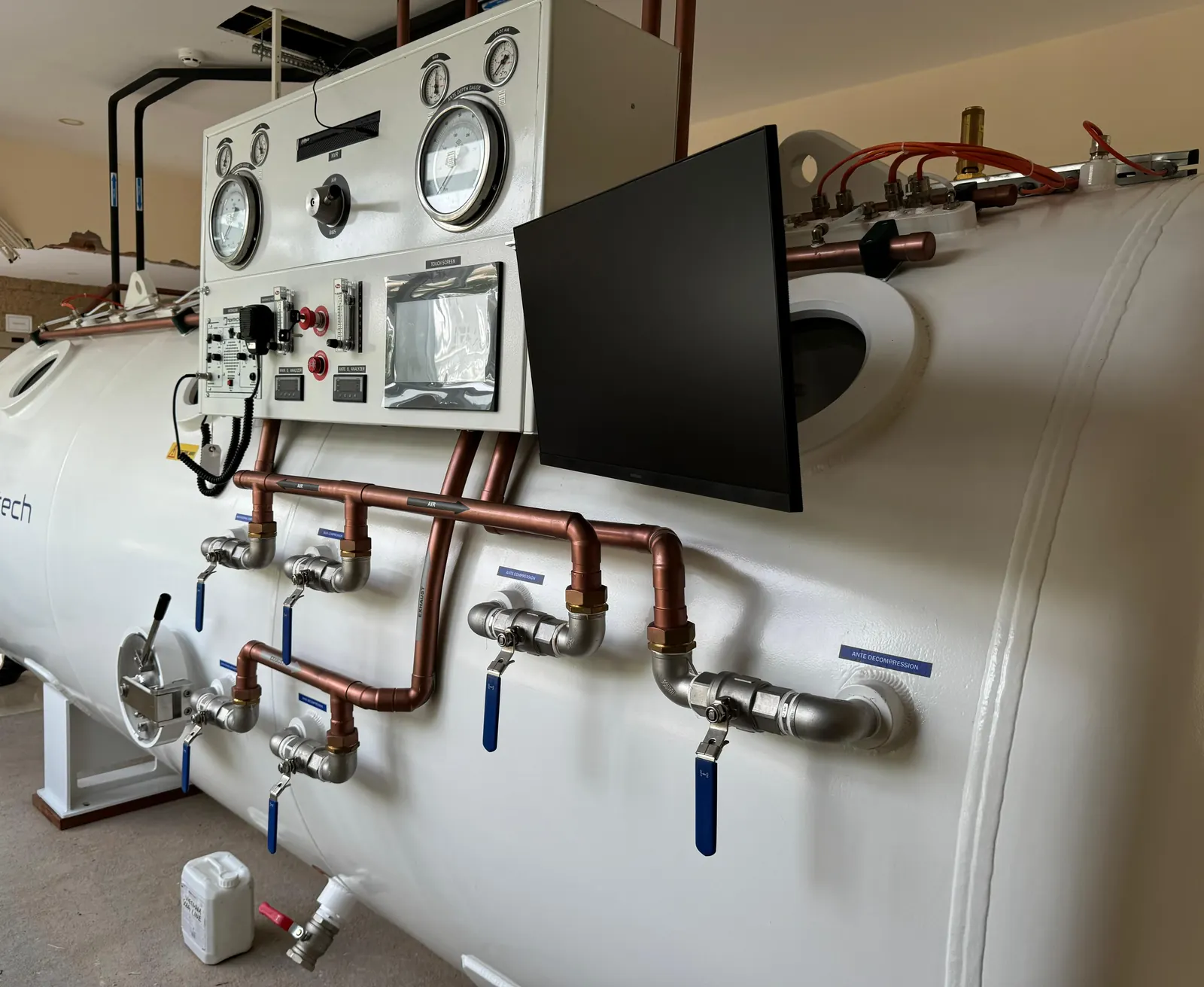 The side of a delivered decompression chamber: the control panel on the hull with the copper and stainless valve manifold running below it