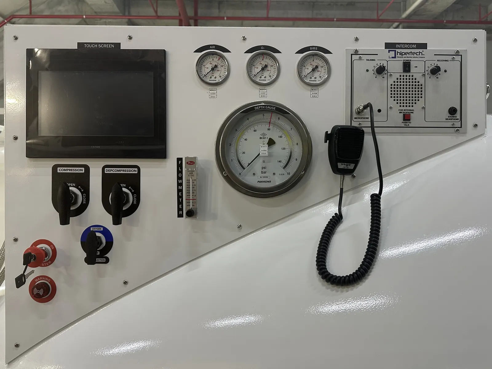 The control panel of a transportable recompression chamber: a touchscreen, air, oxygen and BIBS gauges, a large depth gauge, an intercom and compression selectors