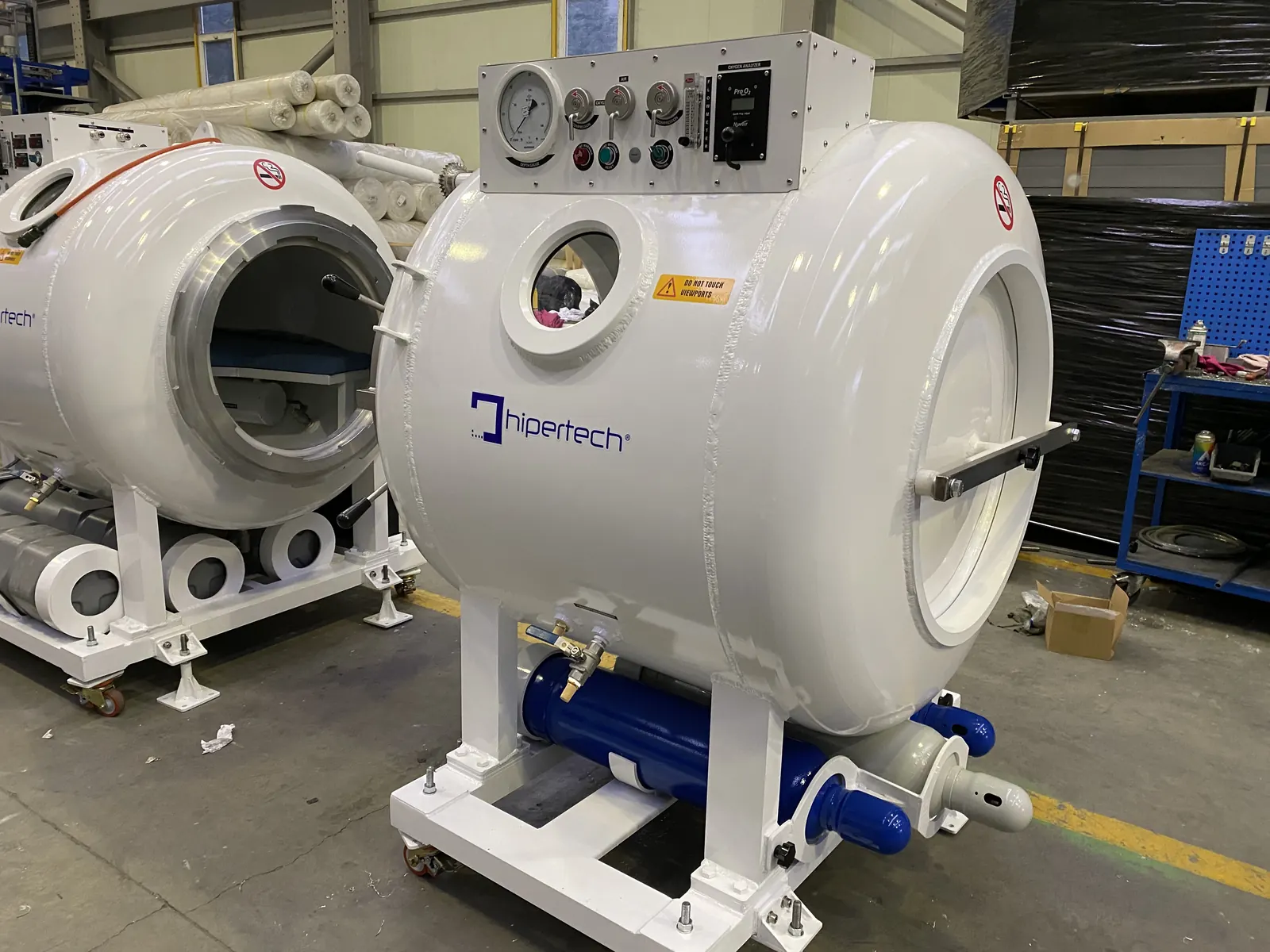Two transportable recompression chambers on castored skids, the nearer with its door closed and the one behind standing open