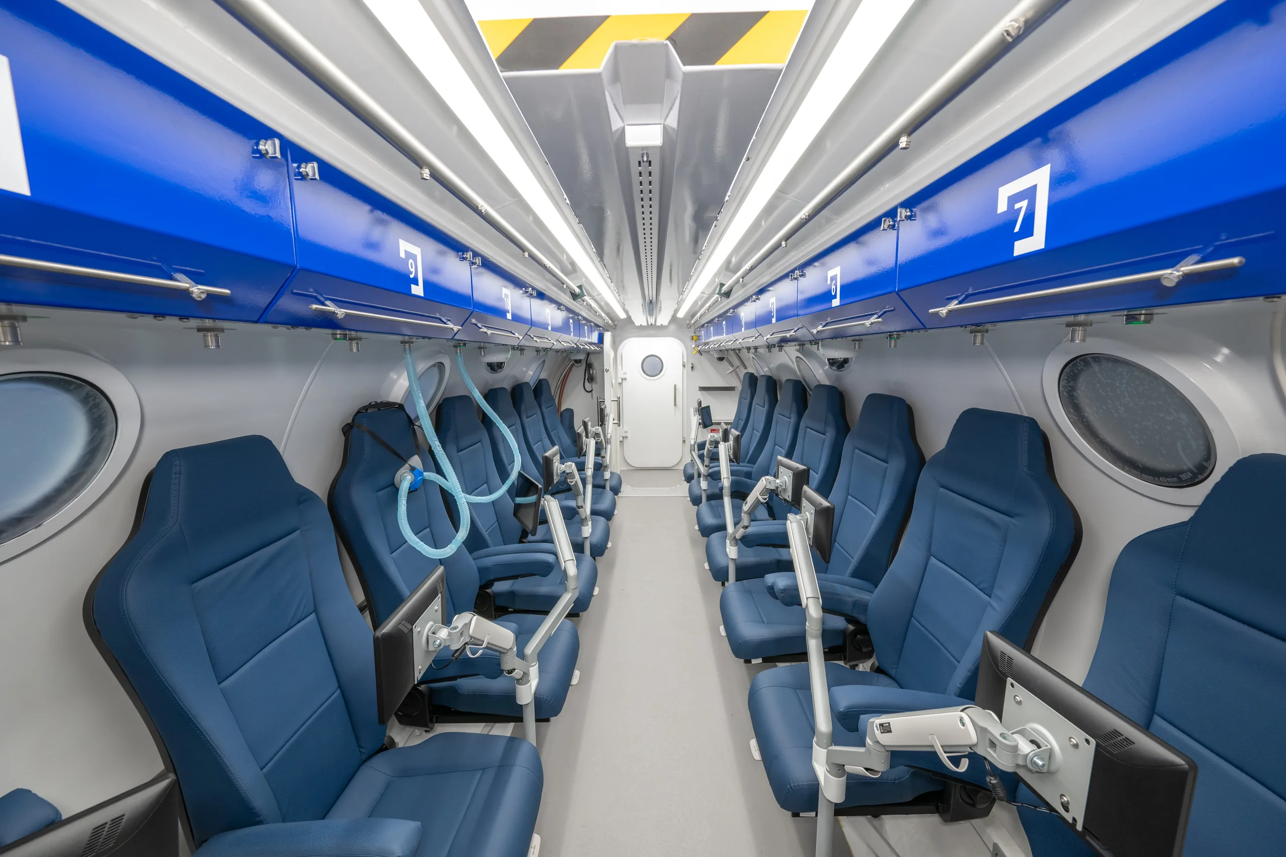 Interior of a Hipertech multiplace hyperbaric chamber with navy ergonomic seating, installed at Horacio Oduber Hospital, Aruba