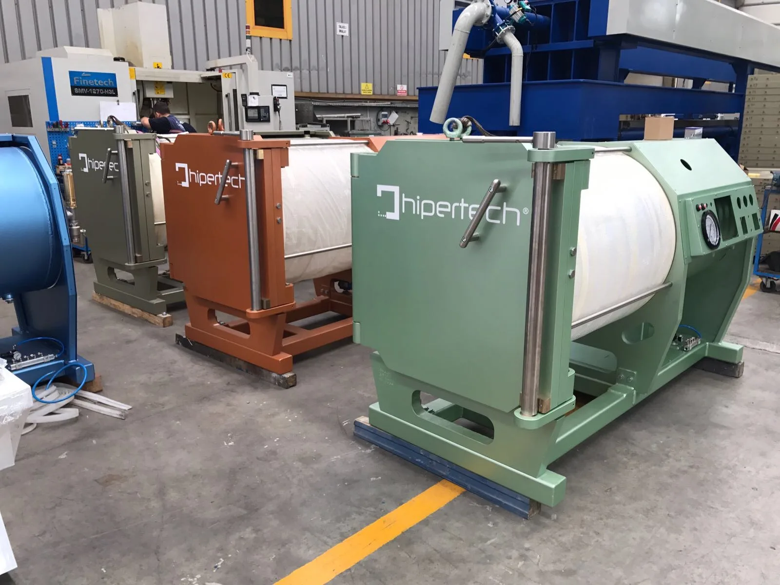 Monoplace chambers in different frame colours on the Hipertech factory floor, a pale green unit in front