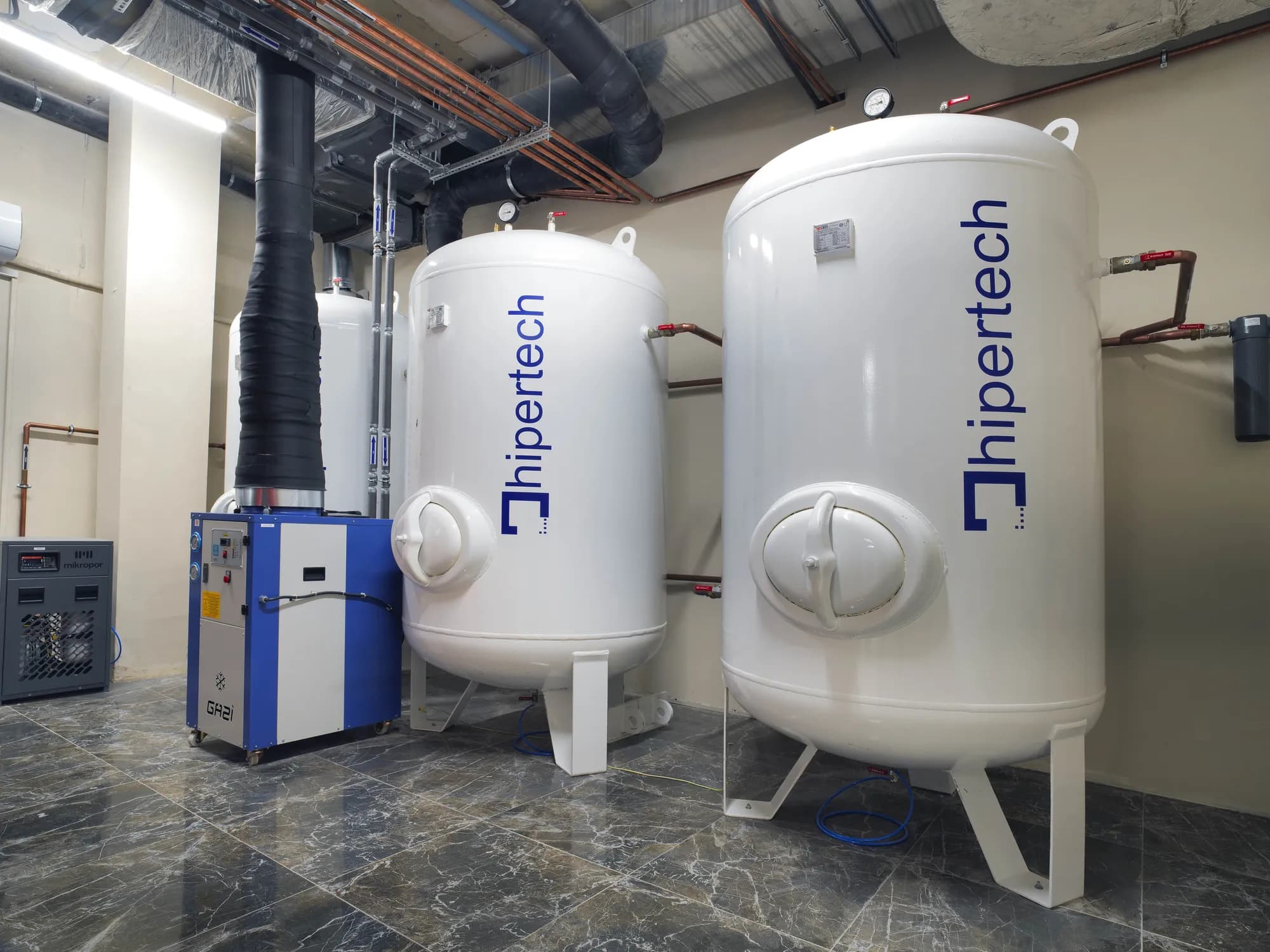 The plant room of a delivered center: two Hipertech air receivers with copper pipework, a compressor and a refrigerated dryer
