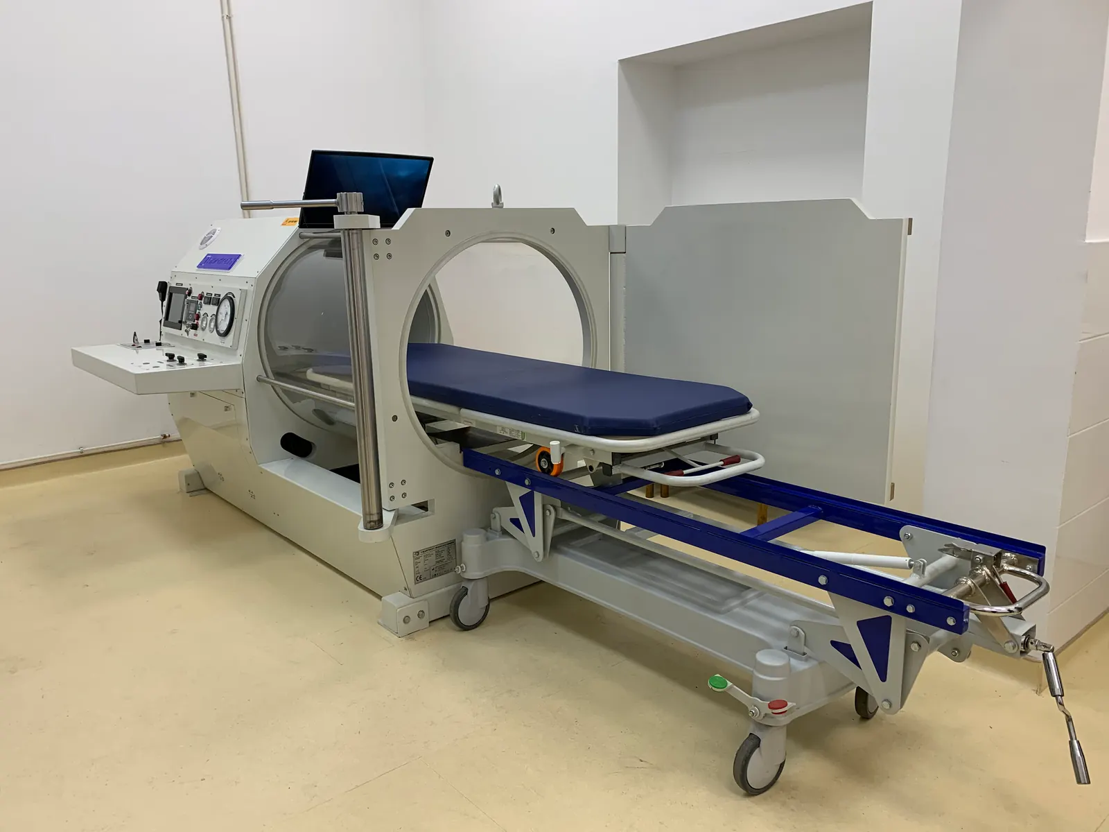 A monoplace chamber with its internal stretcher run fully out of the open end onto its own wheeled trolley