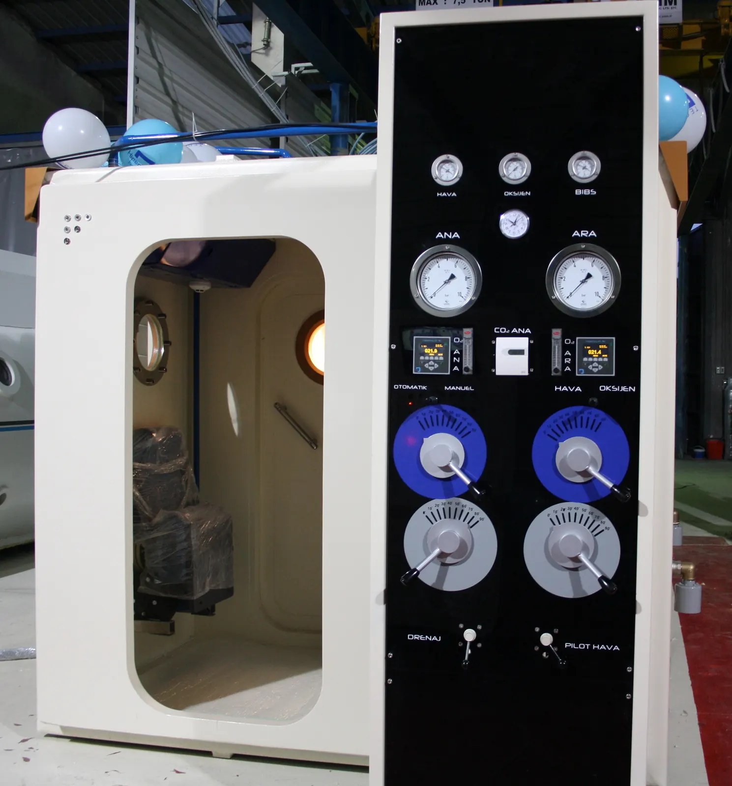 The rectangular entry door of a Multiplace Quadro standing open in a cream end frame, beside the black console face carrying its gauges and valves